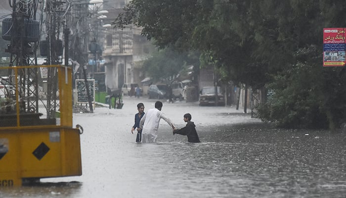 People wade through the flooded street after during the monssoon rain in Rawalpindi, July 17, 2025. — Reuters